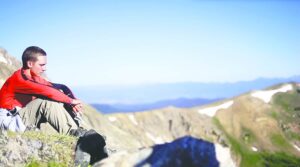 A youth prays atop a mountain during Camp Wojtyla, a Catholic summer camp. Pope Francis discusses humanity's relationship with creation in his encyclical Laudato Si.