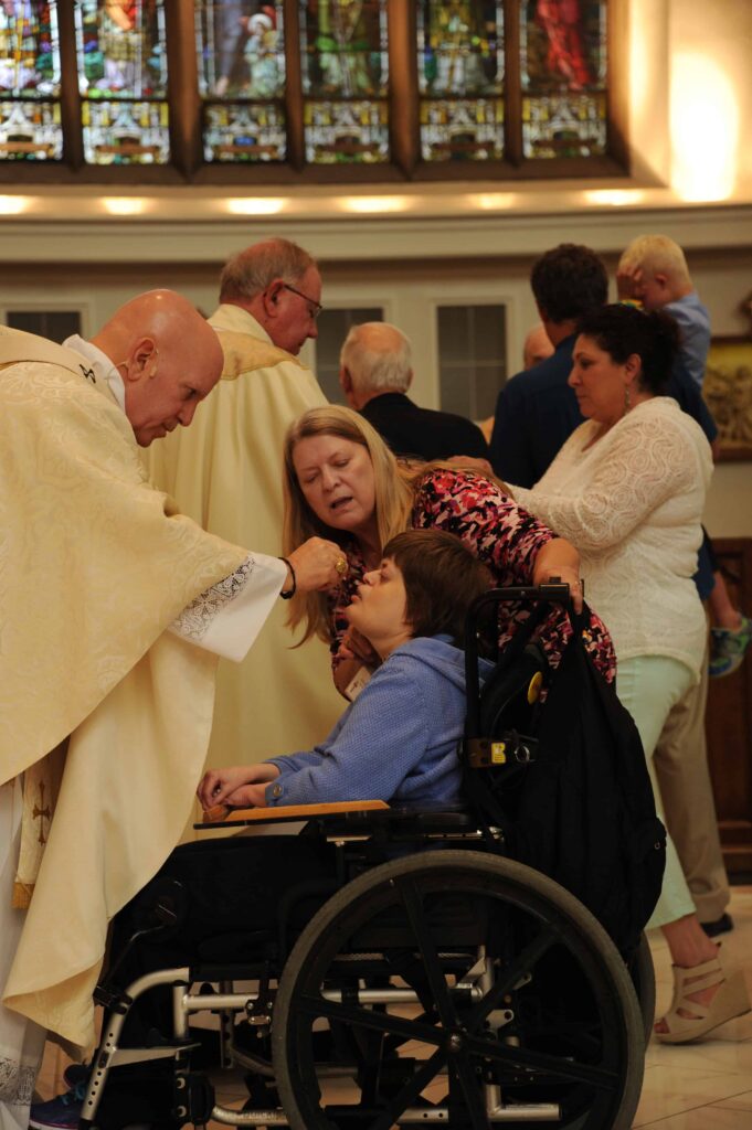 Archbishop Aquila hosts gives a participant in the Special Education Mass Holy Communion. Students and their families were all invited to attend. (Photo by Bernard Grant/Denver Catholic)