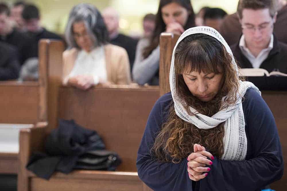 DENVER, CO - APRIL 3: Eva Bueno kneels in prayer during the Celebration of the Lord's Passion on Good Friday at the Cathedral Basilica of the Immaculate Conception April 3, 2015 in Denver, Colorado. (Photo by Daniel Petty/Denver Catholic)
