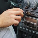 Man’s hand tuning radio in the car.