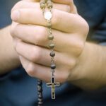 man prays with a rosary in hands