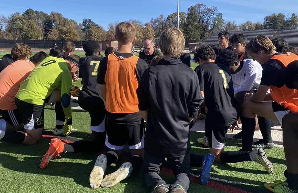 The BMHS Boys varsity soccer team kneels in prayer following their win in the semi-final game against Teullride on Nov. 4. (Photo provided)